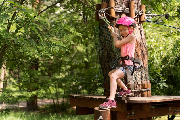 Menina bonita se divertindo em um parque de aventura