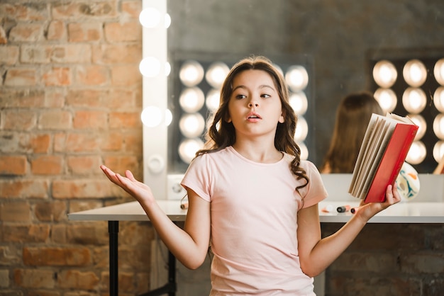 Menina bonita segurando o livro ensaiando nos bastidores