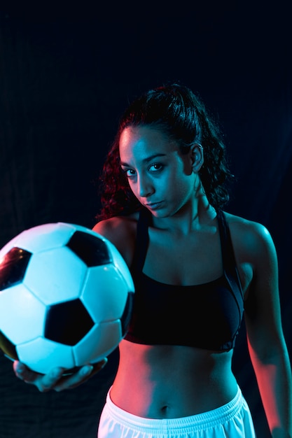 Menina bonita vista frontal, segurando uma bola de futebol