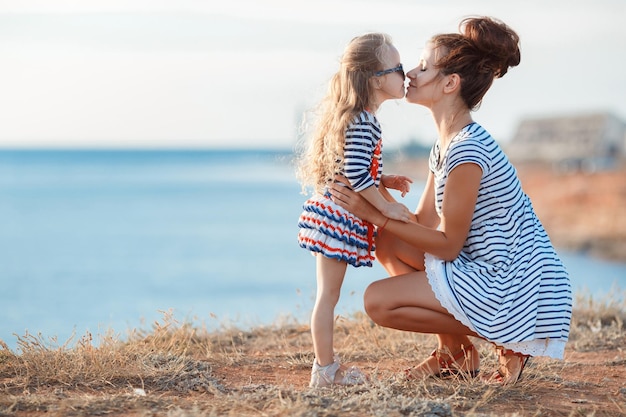 Menina bonitinha com a mãe perto do mar