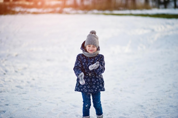 Menina bonitinha com trenós pires ao ar livre em dia de inverno