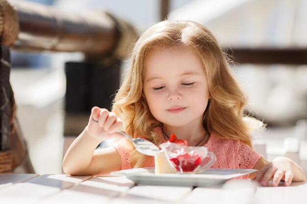 menina bonitinha comendo sobremesa no terraço do café