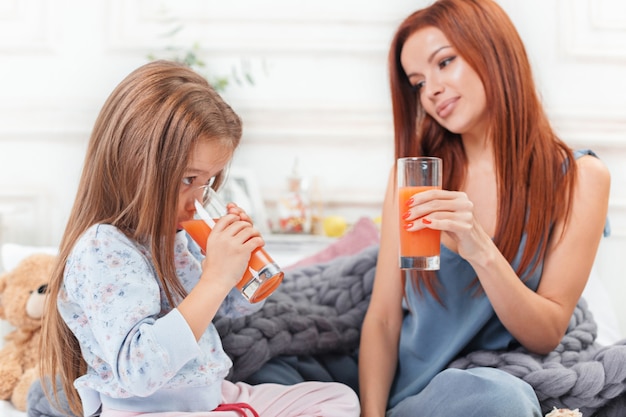 menina bonitinha curtindo, brincando e criando com suco com a mãe