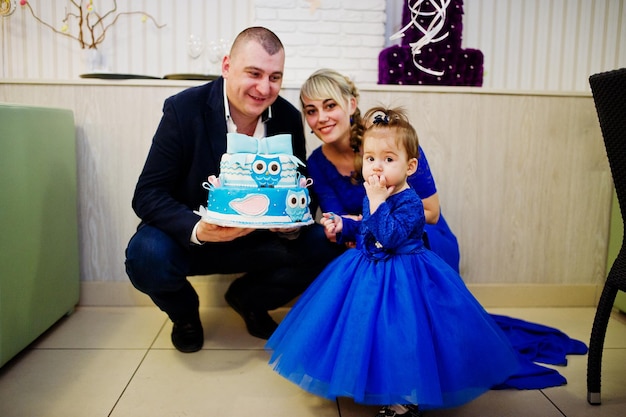 Foto grátis menina bonitinha de vestido azul com bolo de aniversário de 1 ano pai e mãe