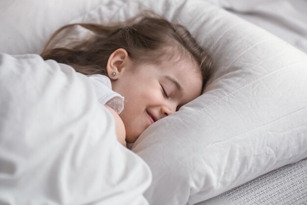 Menina bonitinha dorme docemente na cama