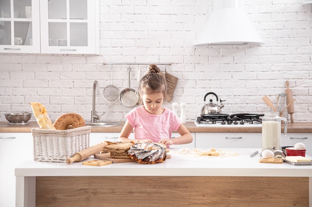 menina bonitinha é cozinhar bolos caseiros na cozinha.