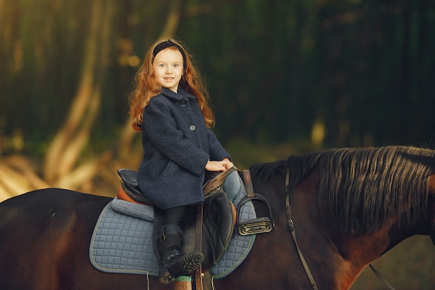 Menina bonitinha em um campo de outono com cavalo