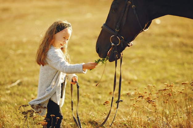 Foto grátis menina bonitinha em um campo de outono com cavalo