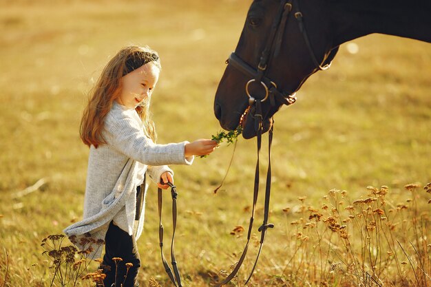 Menina bonitinha em um campo de outono com cavalo