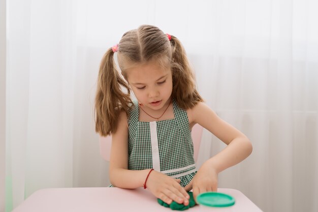 Menina bonitinha moldes de plasticina na mesa