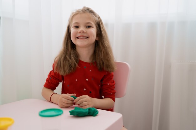 Menina bonitinha moldes de plasticina na mesa