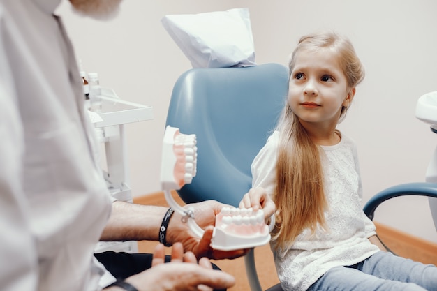 Menina bonitinha sentada no consultório do dentista