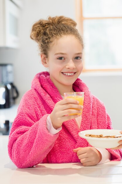 Menina bonito que tem o pequeno almoço na cozinha