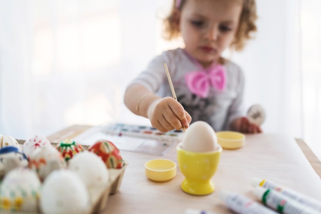 Menina borrada pintando ovos