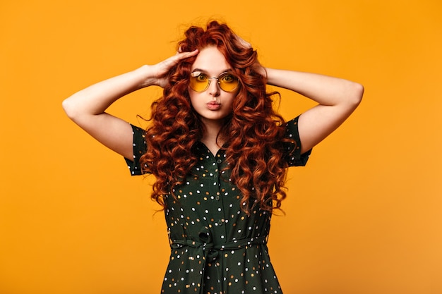 Foto grátis menina branca espantada a brincar com o cabelo encaracolado. mulher caucasiana ruiva olhando para a câmera.