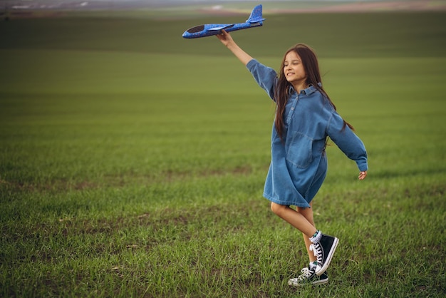 Menina brincando com avião de brinquedo no campo