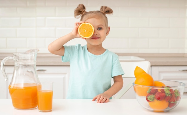 Menina brincando com laranja em casa