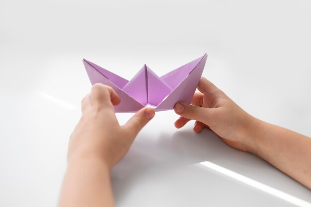 Menina brincando com papel de origami em casa