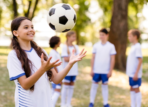 Foto grátis menina brincando com uma bola de futebol lá fora