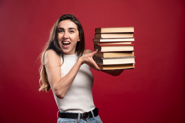 Foto grátis menina carregando uma pilha pesada de livros