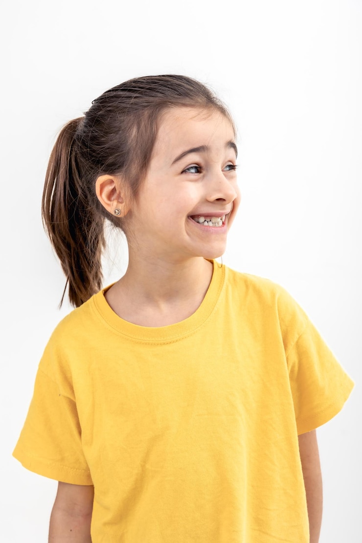 Foto grátis menina caucasiana sorri e desvia o olhar sobre um fundo branco isolado