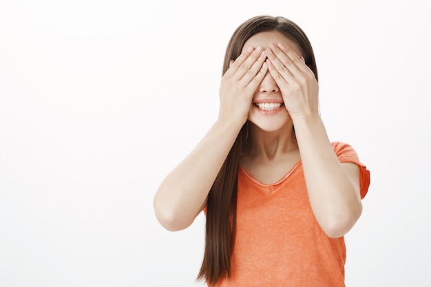 Menina caucasiana sorridente e ansiosa fechando os olhos e contando dez, esperando a surpresa