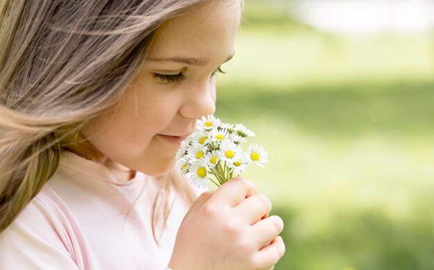 Menina close-up cheirando um buquê de flores do campo