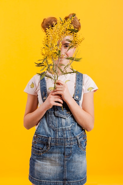 Menina, cobrindo o rosto com galhos de flores