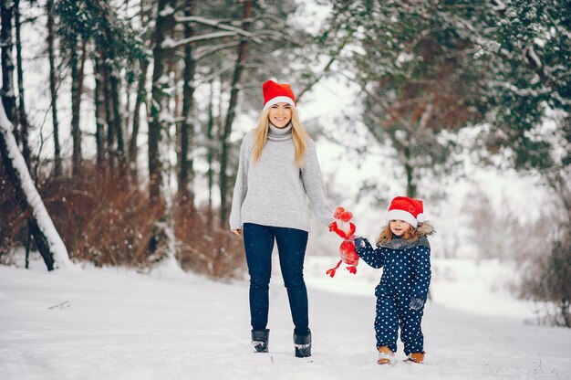 Menina com a mãe brincando em um parque de inverno