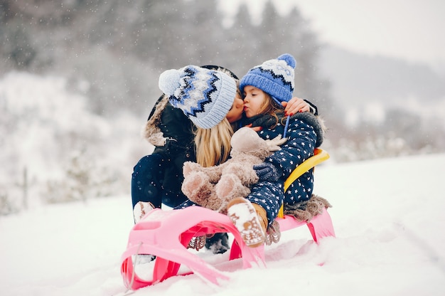 Menina com a mãe brincando em um parque de inverno