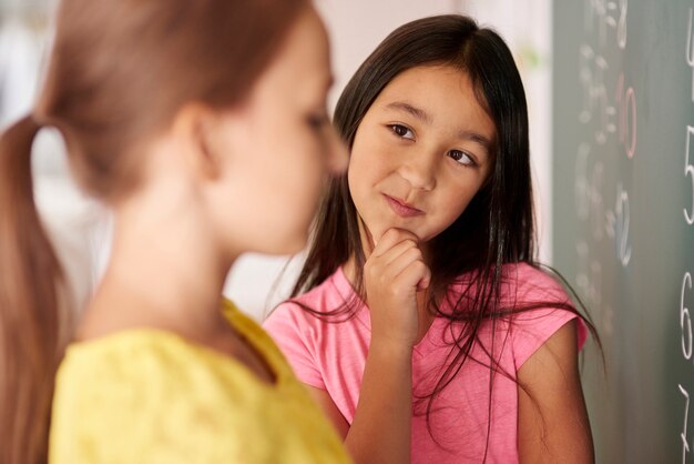 Menina com a mão no queixo olhando para o colega