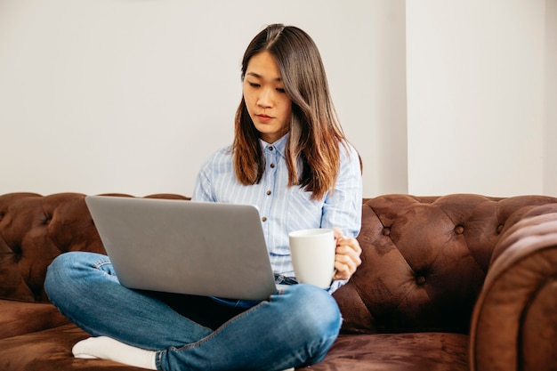 Menina com café e laptop no sofá