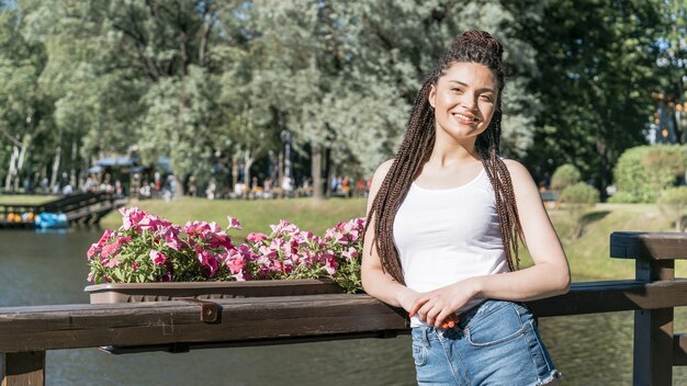 Menina com caixa trança penteado encostado em uma cerca