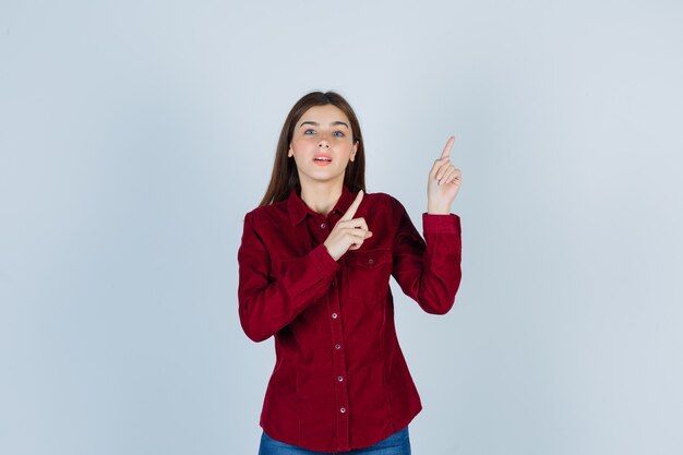 menina com camisa casual apontando para cima e parecendo curiosa