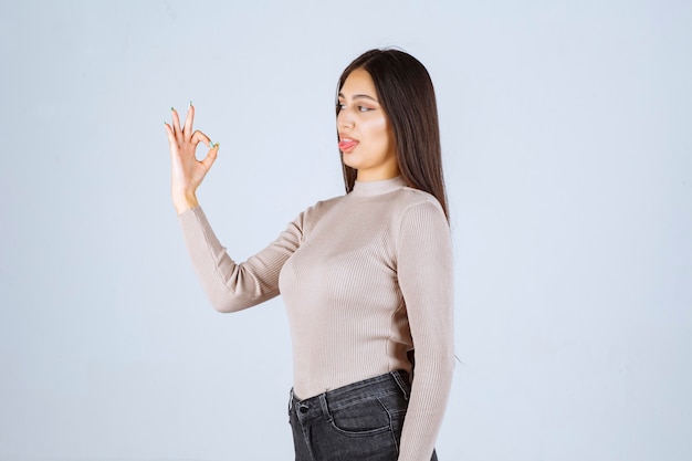 Menina com camisa cinza fazendo meditação.