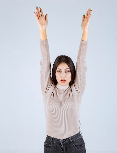Foto grátis menina com camisa cinza, levantando as mãos.