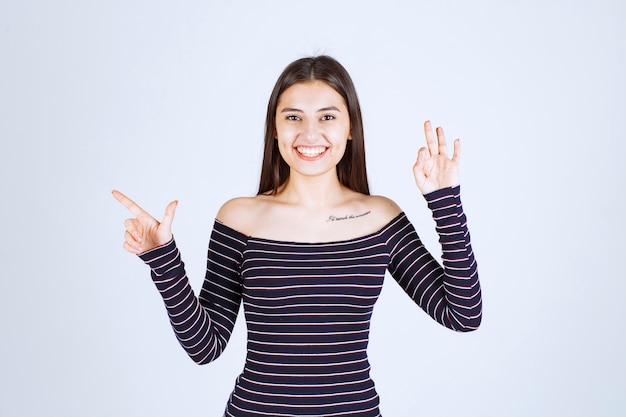 Menina com camisa listrada, mostrando sinal de bom prazer.