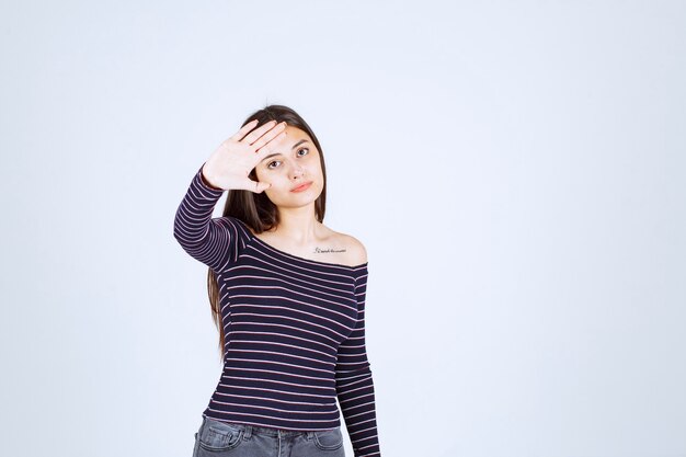 Menina com camisa listrada, parando e impedindo algo.