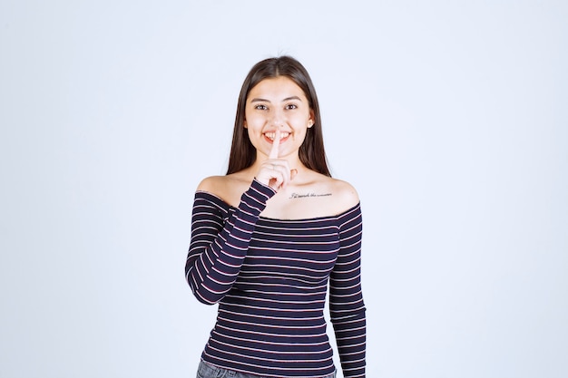 Foto grátis menina com camisa listrada, pedindo silêncio.