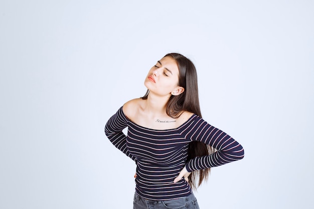 Foto grátis menina com camisa listrada tem uma dor nas costas.