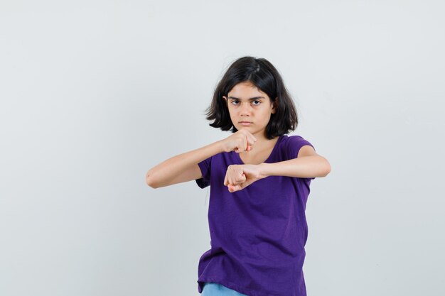 Menina com camiseta em pé em pose de luta e parecendo malvada