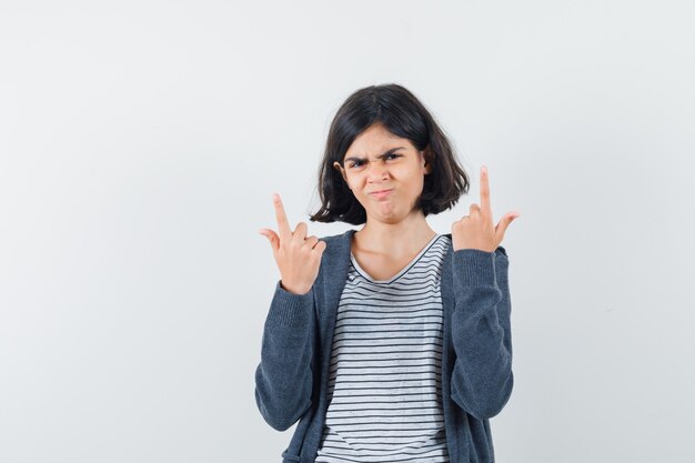 Menina com camiseta, jaqueta apontando para cima e parecendo confiante