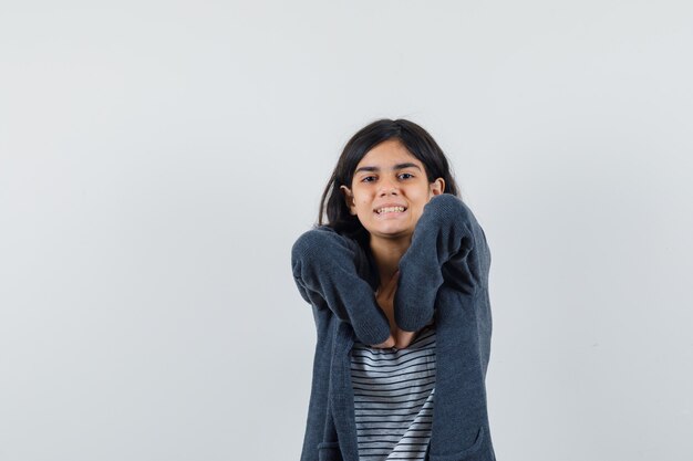 Menina com camiseta, jaqueta esticando os cotovelos e parecendo relaxada