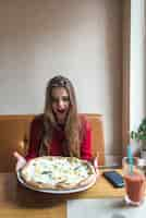 Foto grátis menina com cara engraçada segurando uma pizza de queijo