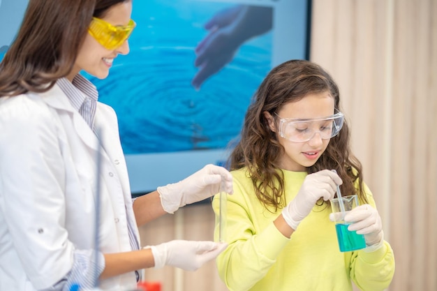 Menina com copo com líquido e mulher sorridente