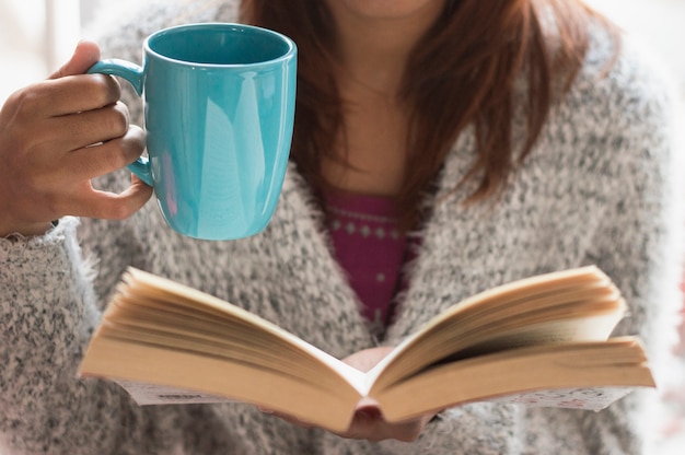 Menina com copo e livro aberto