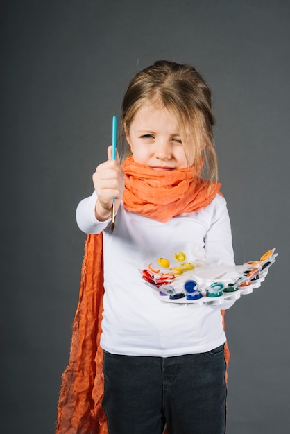 Foto grátis menina com cores de água e pincel nas mãos