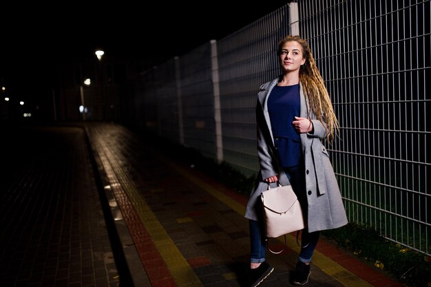 Menina com dreadlocks andando na rua noturna da cidade