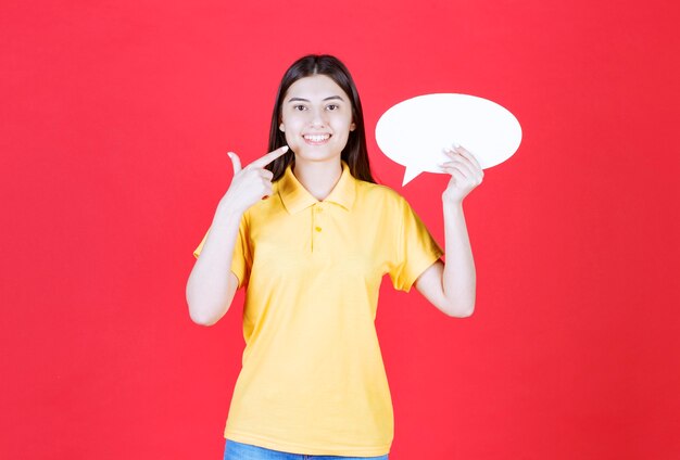 Menina com dresscode amarelo segurando um quadro oval de informações