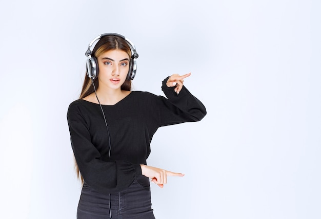 Menina com fones de ouvido, mostrando o tamanho de um objeto. Foto de alta qualidade